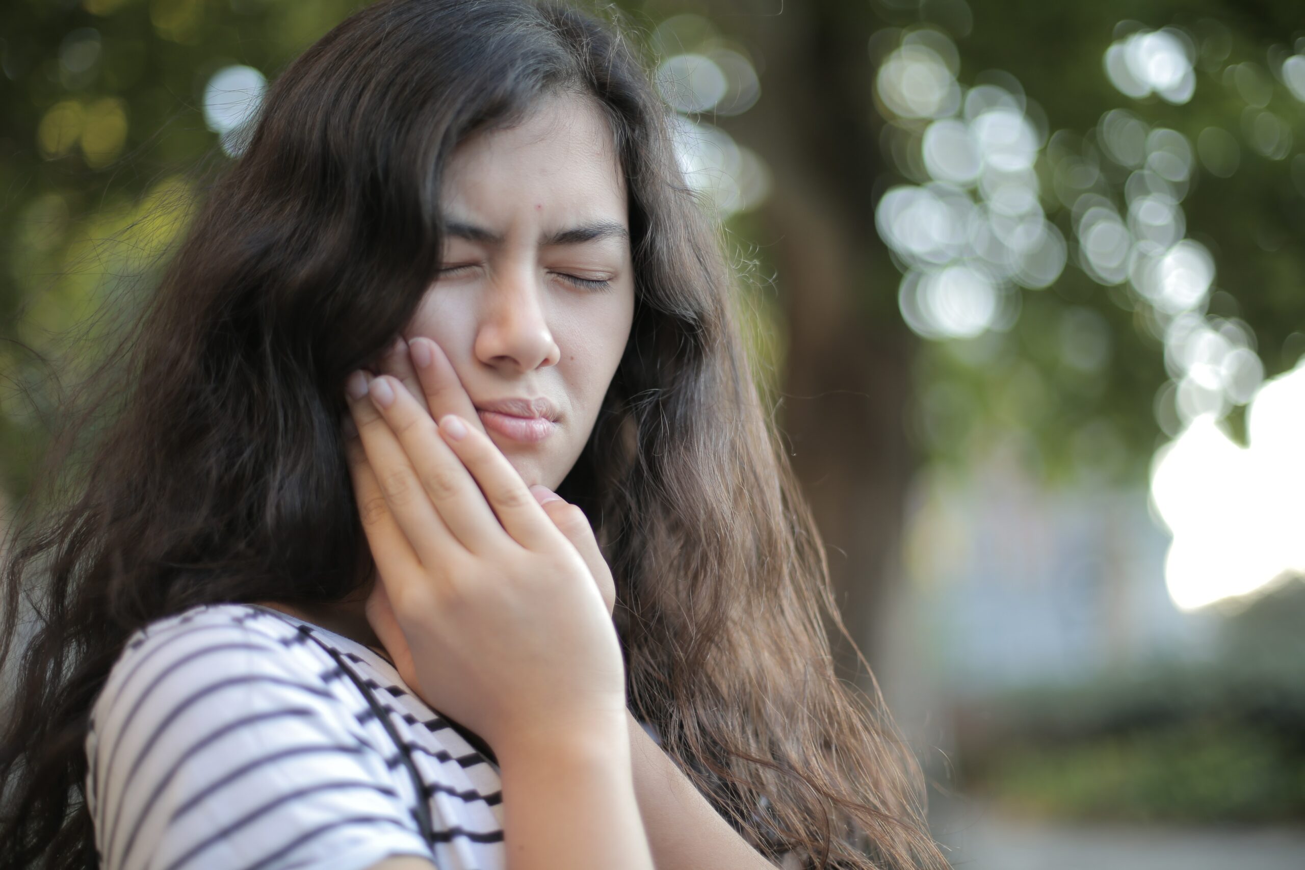tooth pain girl holding mouth from tooth pain