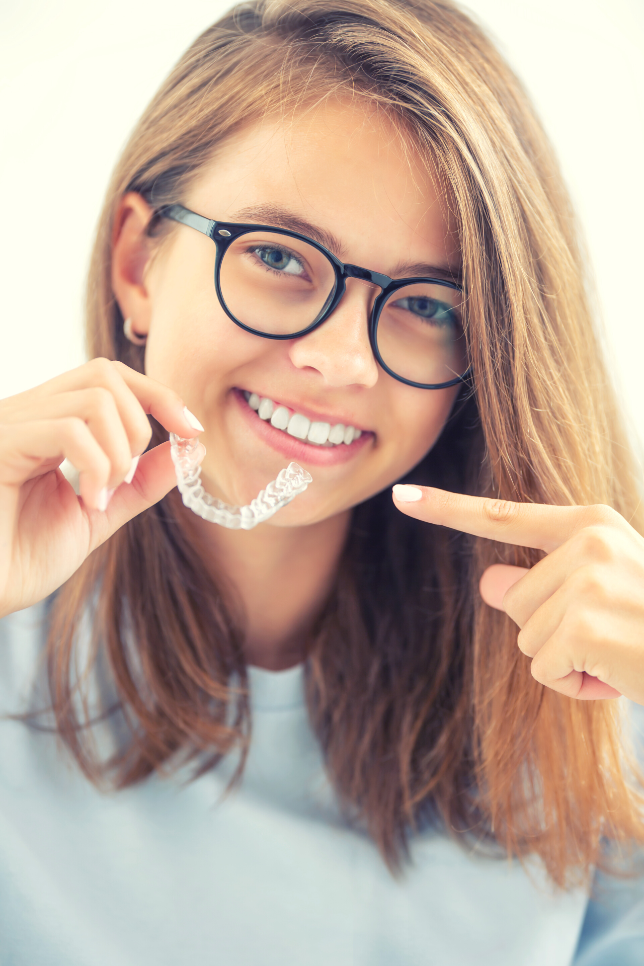 invis aligners child holding up Invisalign clear aligner trays
